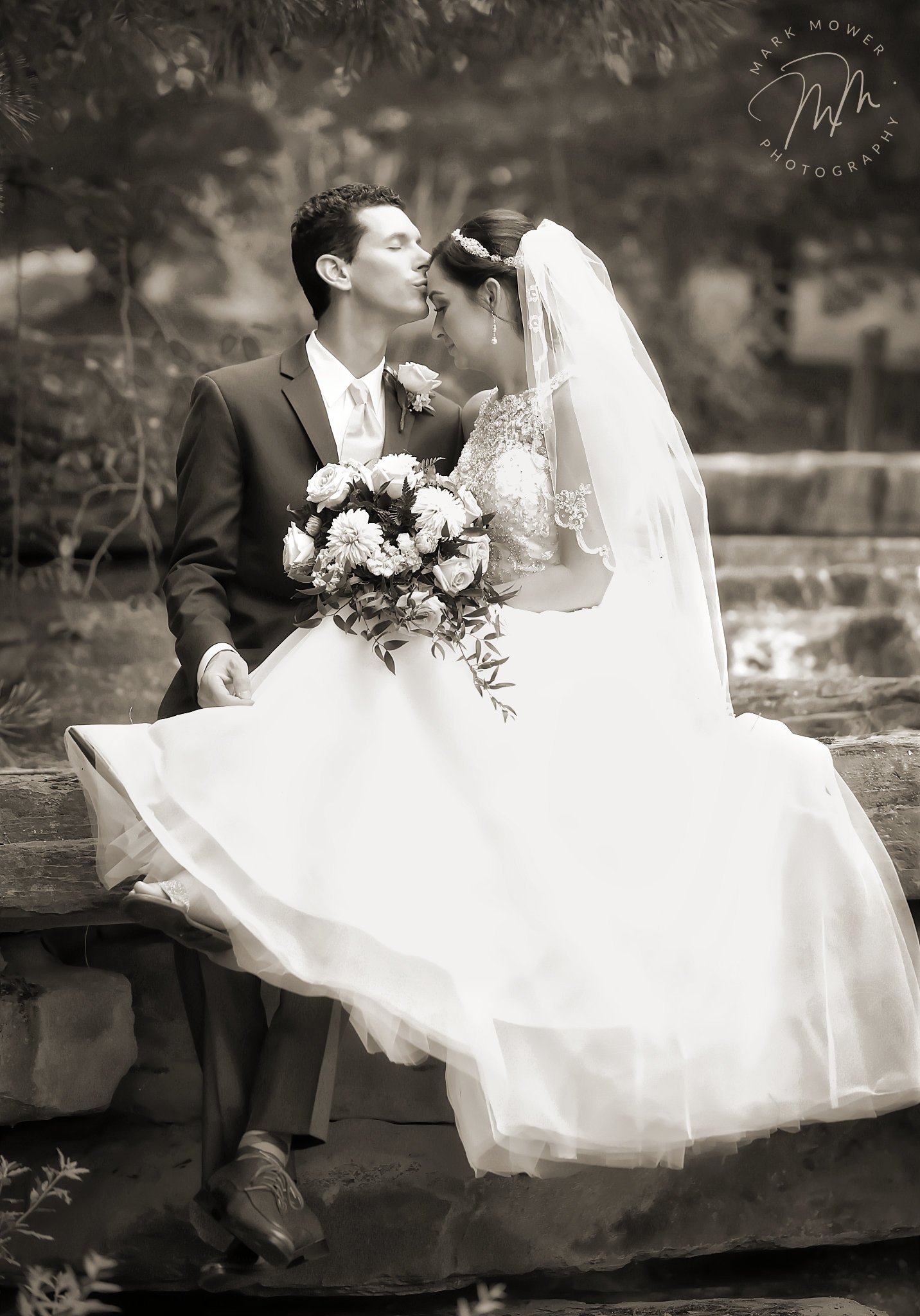 Black and white wedding portrait — couple seated outdoors